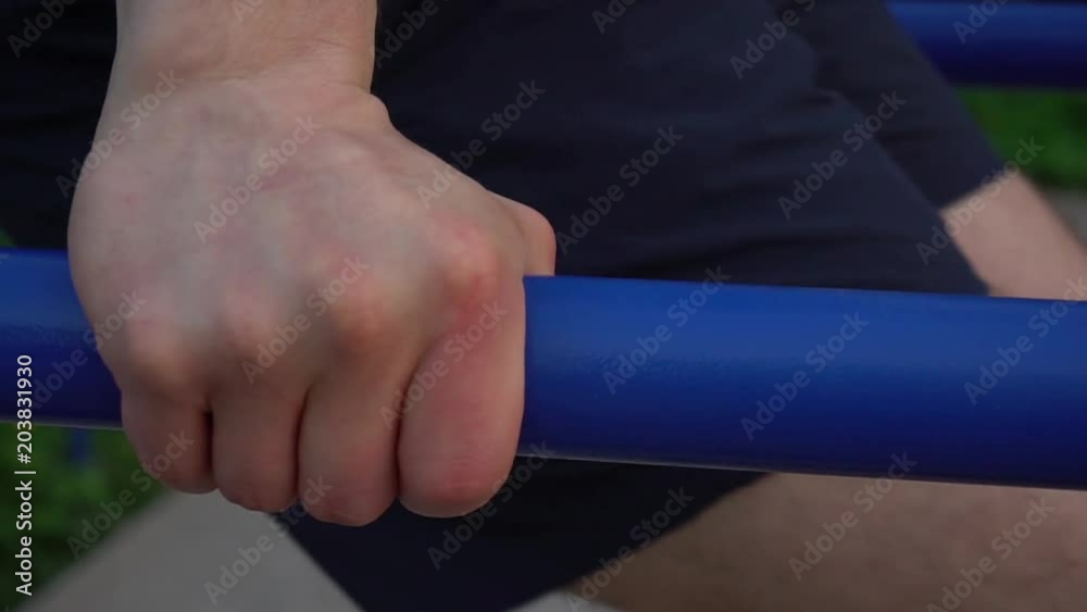 Close up fist of a sportsman doing exercise on parallel bars outdoor. Close up fist of a sportsman doing exercise on parallel bars outdoor.