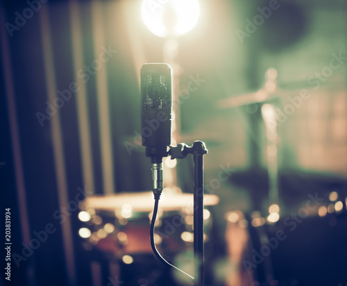 Slika na platnu Microphone in recording Studio or concert hall close-up, with drum set on background out of focus