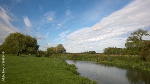 Beautiful landscape scene of the rolling green grass fields in the countryside by the River Cam in Granchester in Cambridgeshire East Anglia England on a bright Summer day with blue skies and trees  photo