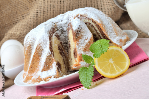 Detail of sliced homemade marble cake sprinkled with sugar, lemon, melissa, milk, eggs and butter photo