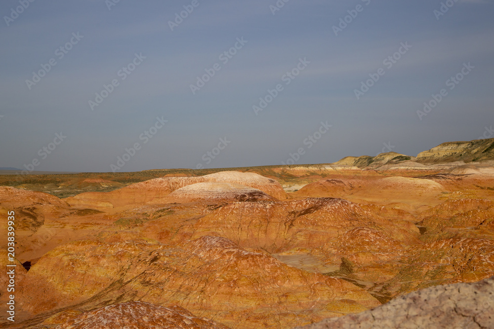 Obraz premium Small Multicolored red, orange and yellow striped hills under a bright blue sky in Eastern Kazakhstan