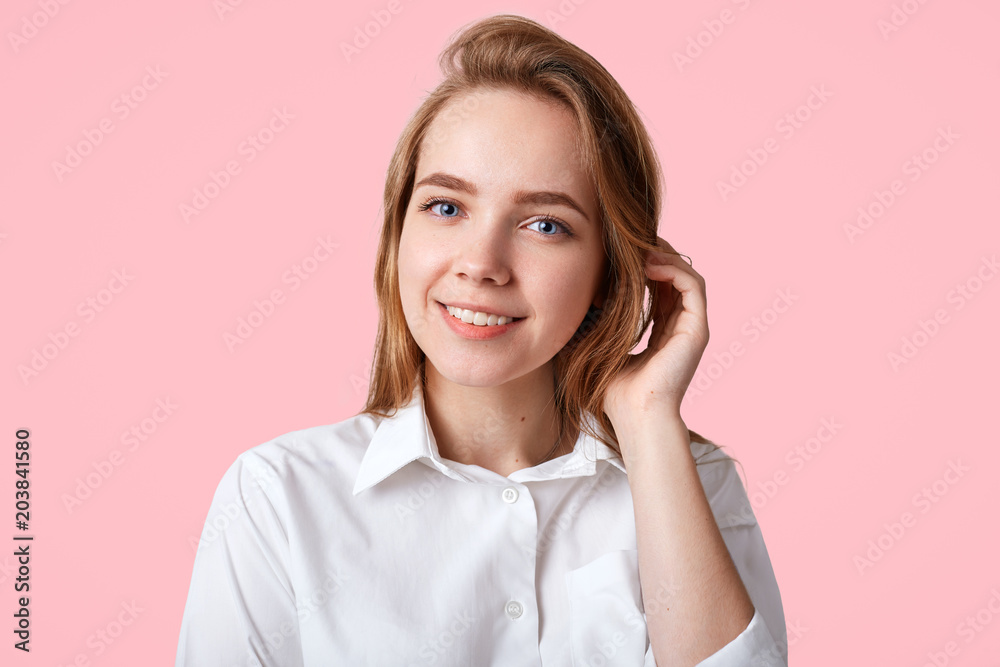 Lovely cute female with positive smile, wears white elegant shirt and stylish cap, going to school or college in good mood, isolated over studio background. Hipster girl spends time with friends Lovely cute female with positive smile, wears white elegant shirt and stylish cap, going to school or college in good mood, isolated over studio background. Hipster girl spends time with friends