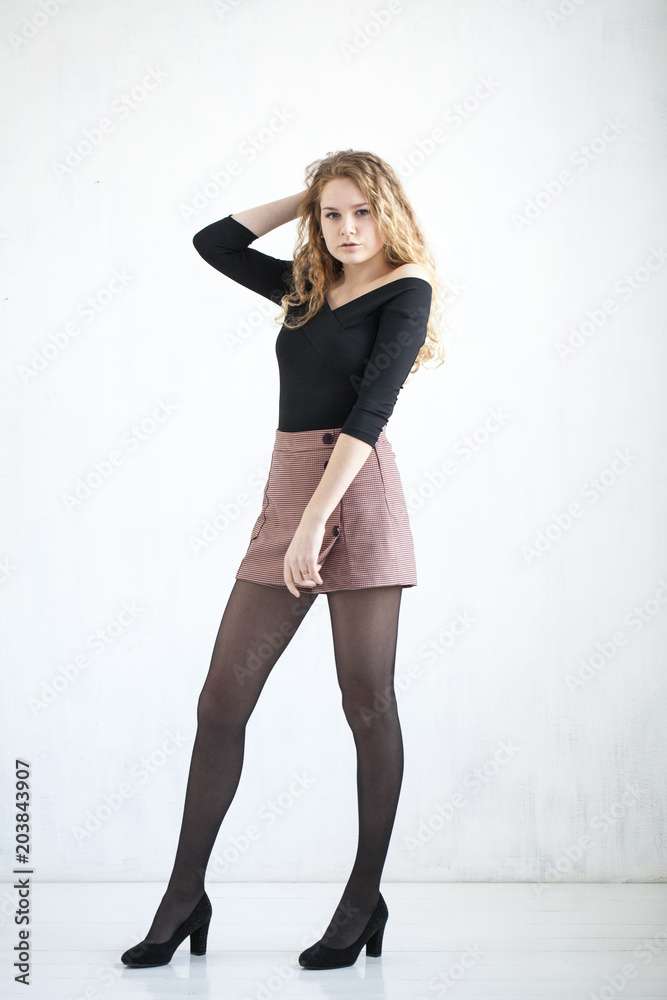 Portrait of full length curly blonde in a black blouse and short skirt