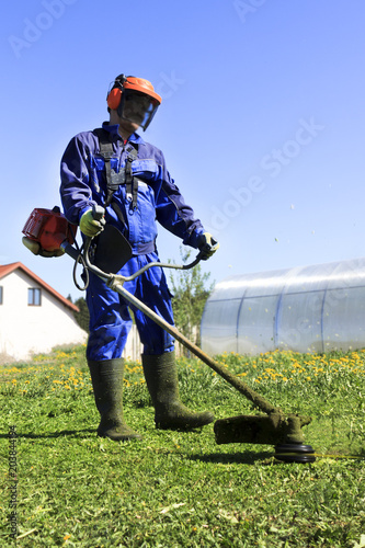 A man in a blue suit. In a protective helmet and headphones. Produces harvesting herbs. The face does not focus