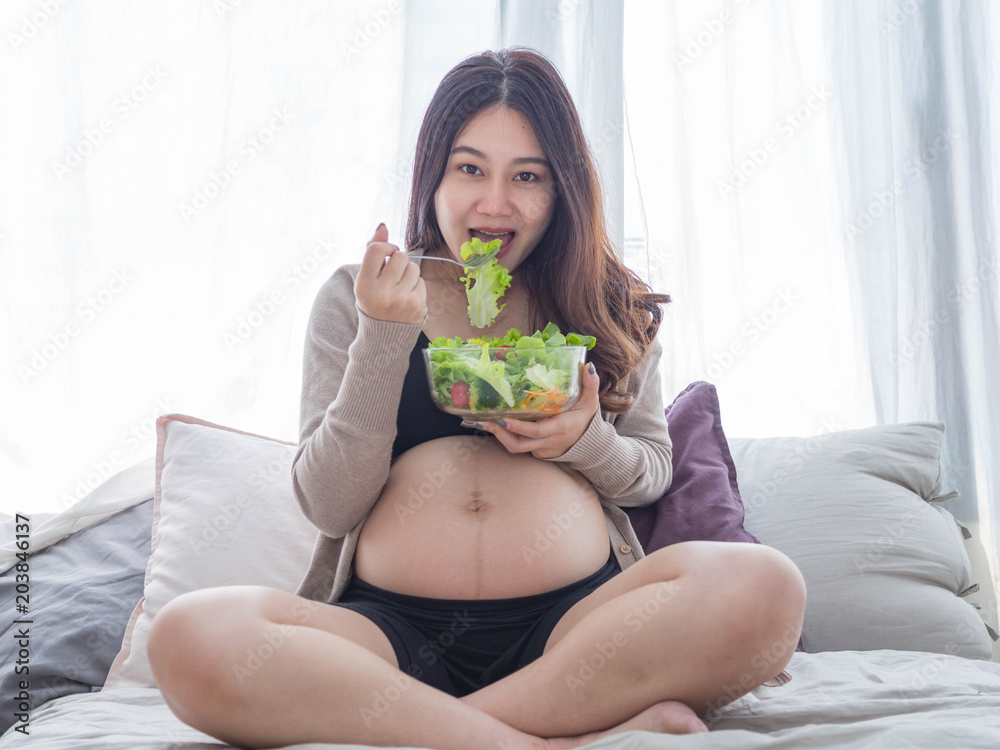 happy pregnant Asian woman eating vegetable salad at home. happy pregnant Asian woman eating vegetable salad at home.