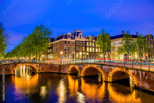 Amsterdam canal with typical dutch houses during twilight blue hour in Holland, Netherlands.