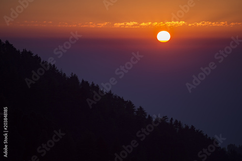 Amazing sunset behind a mountain with the silhouette of trees  Dharamsala  India.