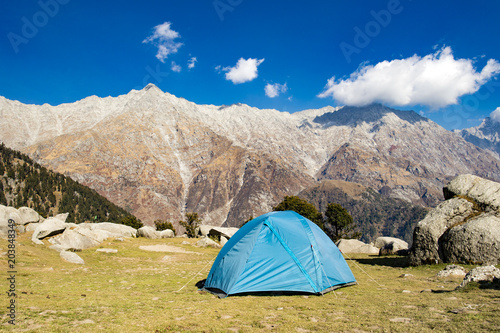 A single blue tent seen against Dhaulahaar peaks of Himalayas in Triund. Sunny day whit some clouds. Dharamshala, Himachal Pradesh. India © Travel Wild