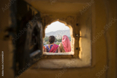 Photography Two Indian girls wearing the traditional Indian dress 'Saree' are admiring the landscape of Jaipur