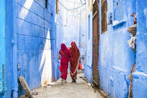 Two women dressed in the traditional Indian Saree are walking through the narrow streets of the blue city of Jodhpur, Rajasthan, India.