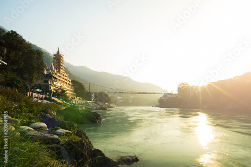 Obraz na płótnie View of Ganga river embankment, Lakshman Jhula bridge and Tera Manzil Temple, Trimbakeshwar in Rishikesh during the sunset. India. w salonie