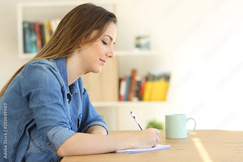 Relaxed woman writing a note on a notebook Relaxed woman writing a note on a notebook