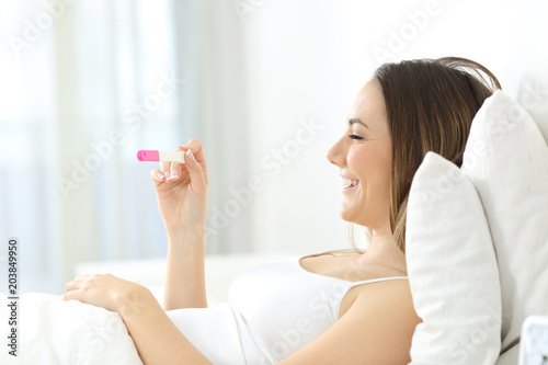 Happy woman checking a pregnancy test on the bed