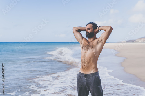 Workout exercise concept.Healthy Handsome Active Man With Fit Muscular Body enjoing sun on the beach at the morning. Sporty Athletic Male Exercising At Beach. Training Outdoor. Sports And Fitness
