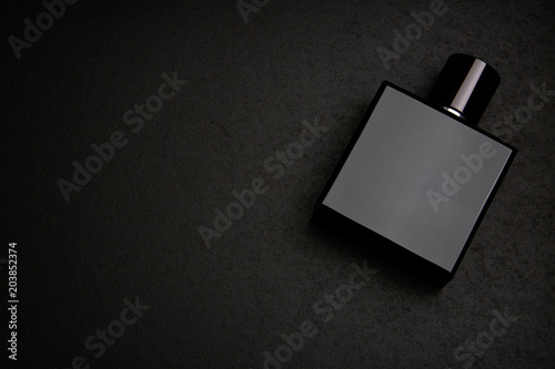 Mockup of black fragrance perfume bottle mockup on dark empty background. Top view. Horizontal photo