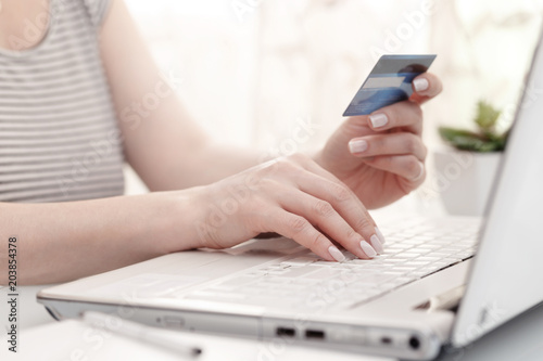 Close up of female hands using modern computer and credit card, high key. Shopping online