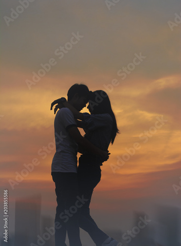 Silhouette teen lovers couple in romantic moment on blurred city downtown background for love story scene concept.