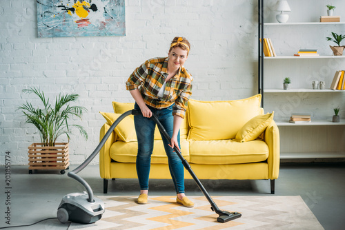 beautiful woman cleaning carpet with vacuum cleaner at home