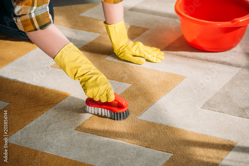 Φωτογραφία cropped image of woman cleaning carpet at home
