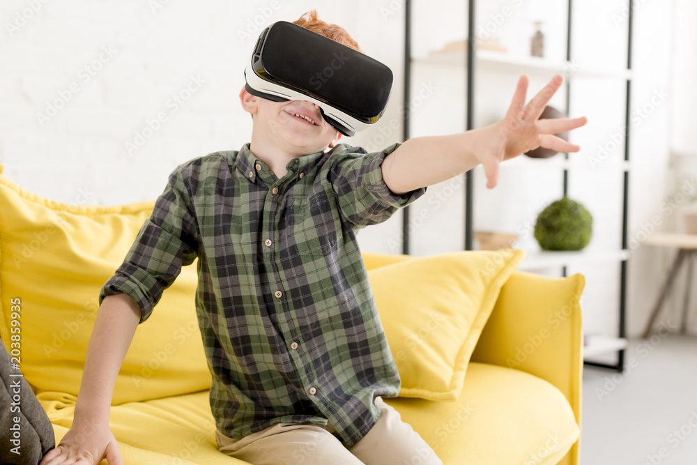 adorable smiling little boy using virtual reality headset at home