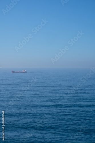 Cloudy horizon and Fog over the sea waves, natural background, red cargo ship on the horizon © jpbarcelos