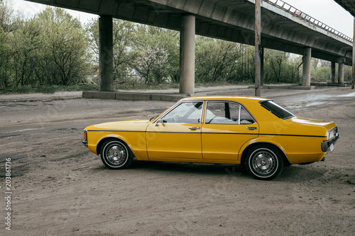 yellow vintage classic car under bridge