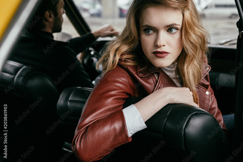 beautiful young woman looking away while sitting in car with boyfriend driving auto