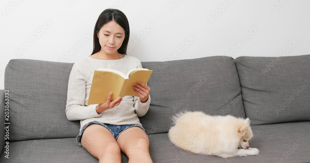 Woman reading book with her dog at home Woman reading book with her dog at home