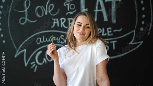 Young woman smelling green dill seasoning vegetable. Mustache from fennel. Fun in the kitchen. The concept of healthy eating. photo