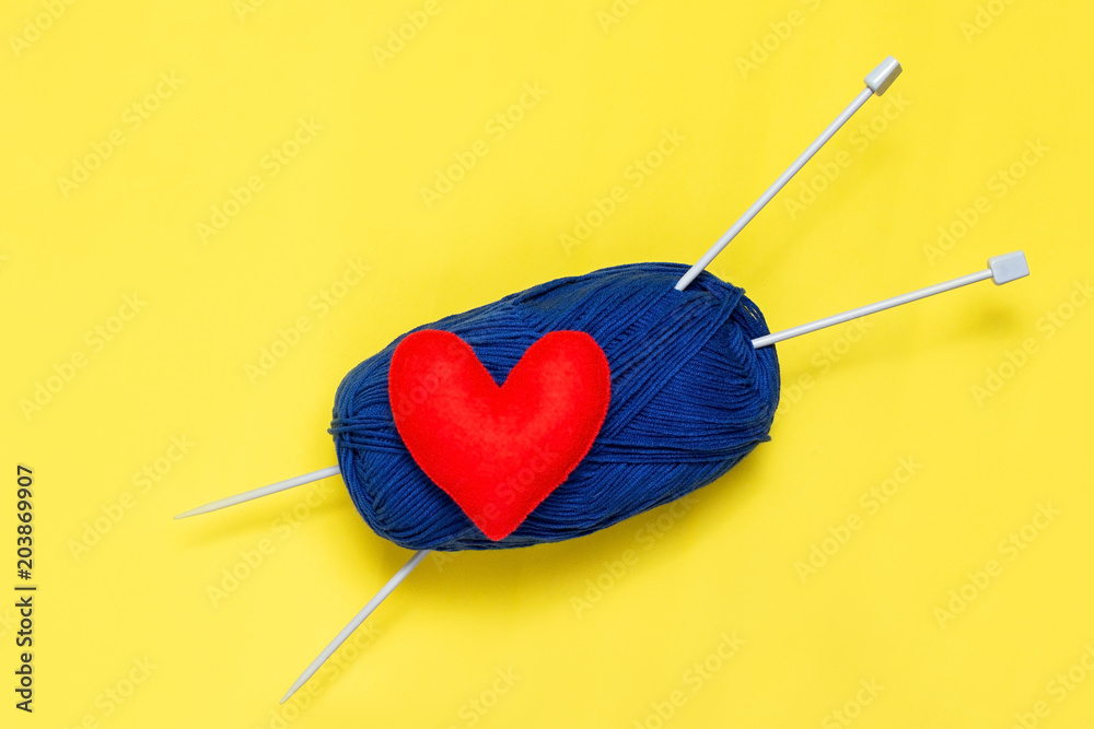 Top view of yarn and red felt heart on yellow background, love to knit image concept Top view of yarn and red felt heart on yellow background, love to knit image concept