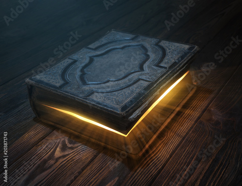 Old magic book on wooden table with light rays coming out form inside