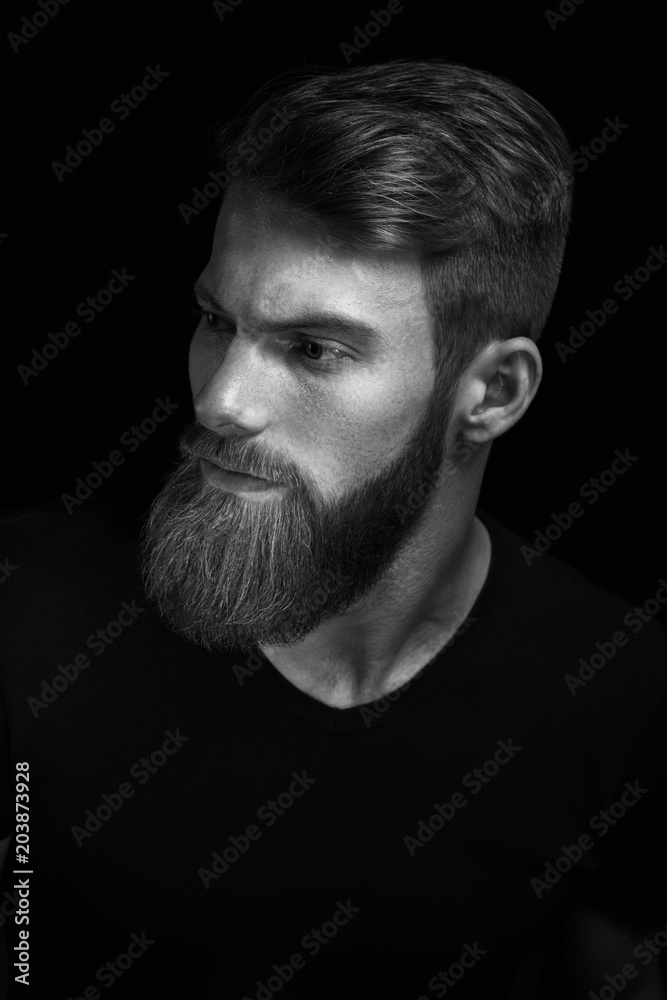 Black and white portrait of puzzled young man looking down over black background