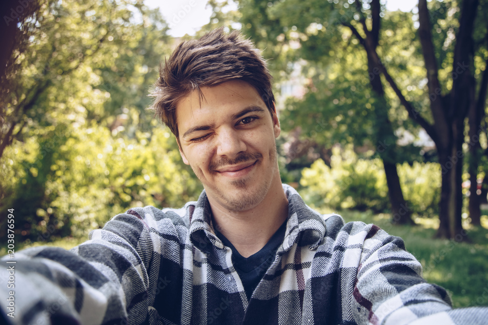 handsome young man looking at the camera and taking a selfie photo outdoors. handsome young man looking at the camera and taking a selfie photo outdoors.
