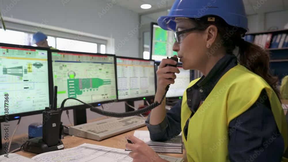 Woman in industrial control room using radio to give instructions