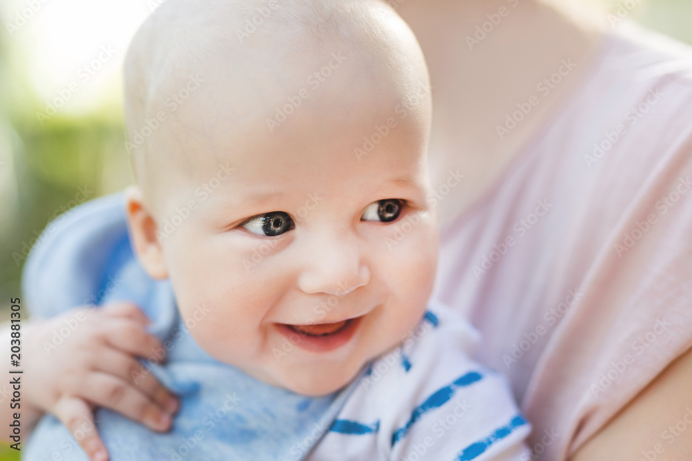 Small baby boy laughing on mothers hand. Little cute child having fun playing outdoor with mom. Happy childhood concept