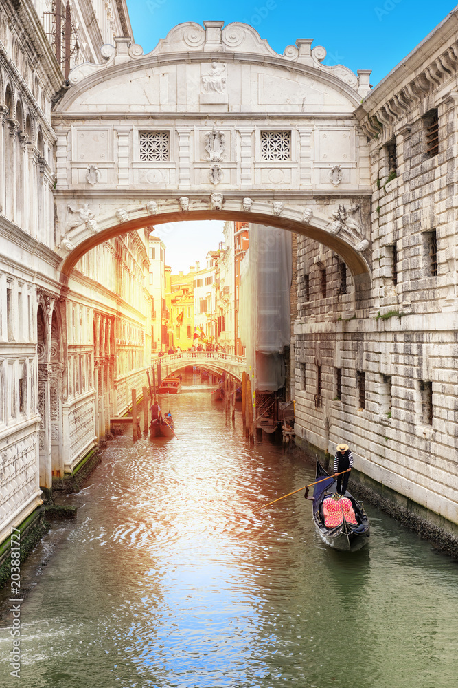 Beautiful view of the bridge of sighs in Venice with rays of sunlight, and Venetian gondola on green canal, Venice, Italy. 