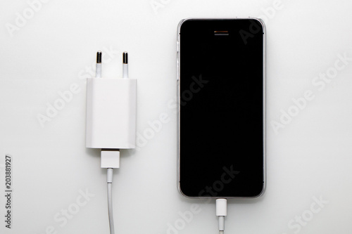 Black smartphone, adapter and cable on a white background