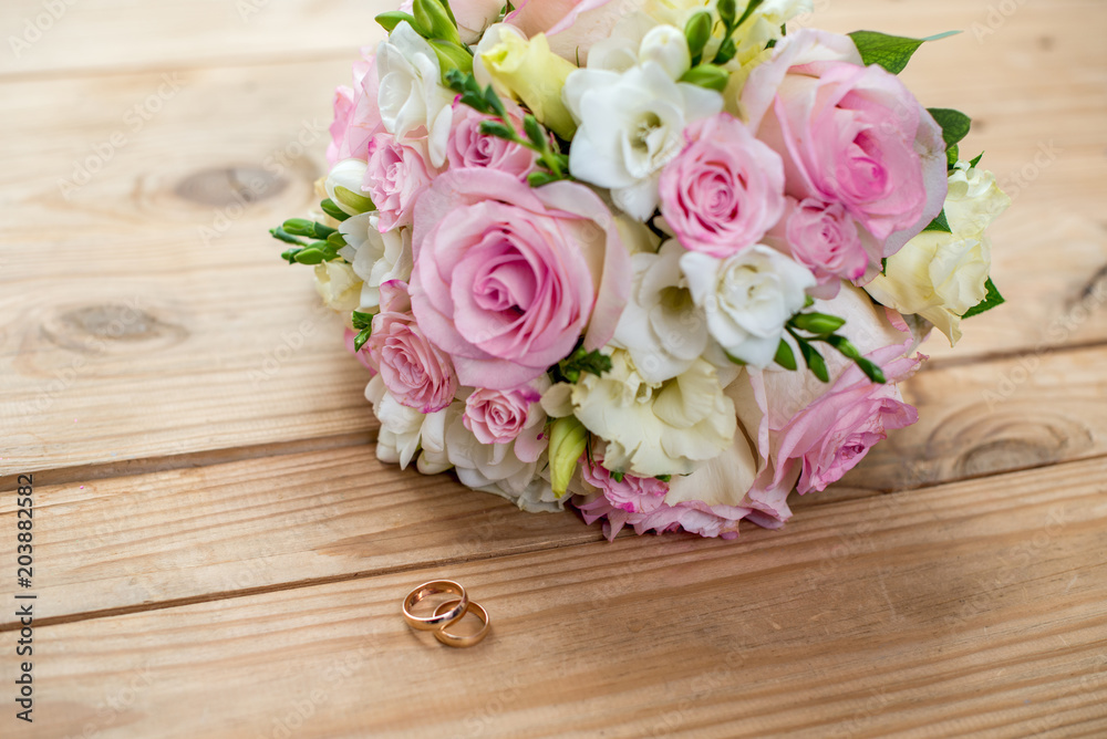 Two gold wedding rings and beautiful wedding are on the brown wood table Two gold wedding rings and beautiful wedding are on the brown wood table