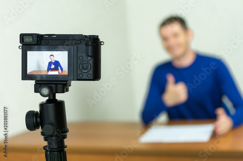 Close up of a video camera filming young smiling male blogger