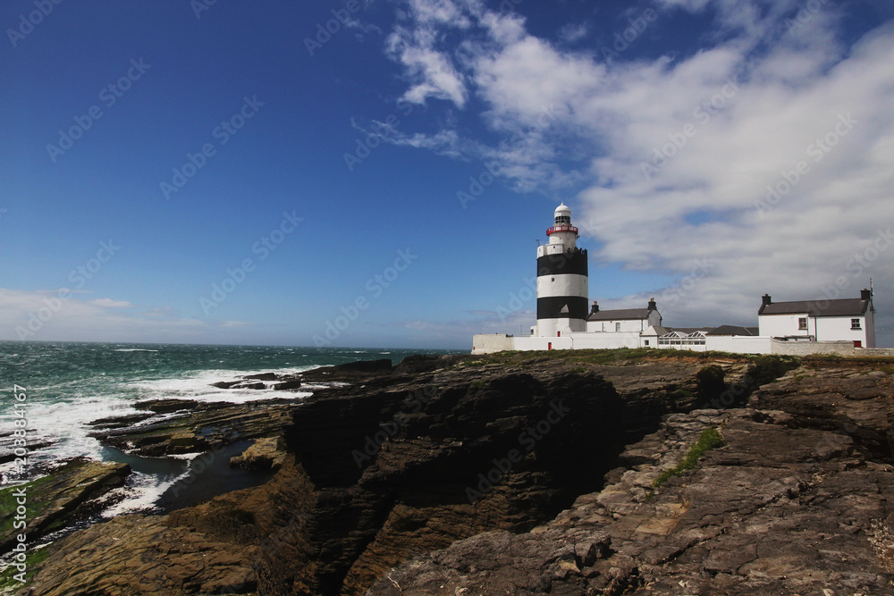 Black and white lighthouse and surrounding landscape at Ireland coastline