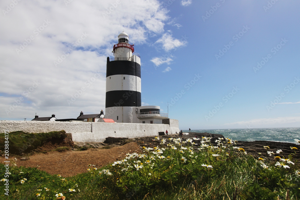 Black and white lighthouse and surrounding landscape at Ireland coastline