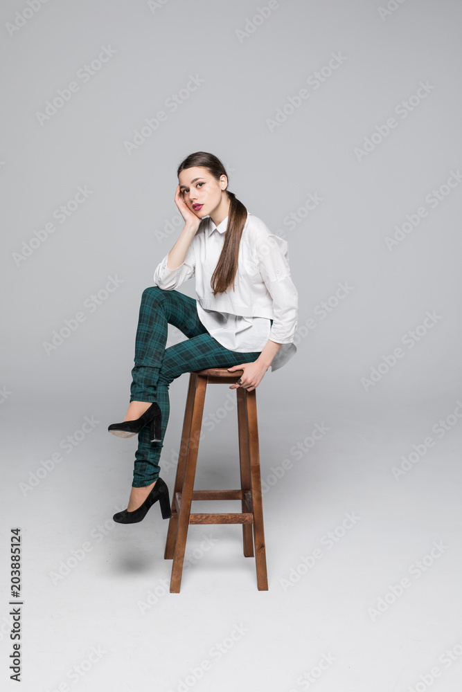Young smiling businesswoman sitting on the chair on gray background Young smiling businesswoman sitting on the chair on gray background