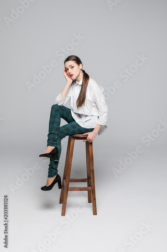 Young smiling businesswoman sitting on the chair on gray background