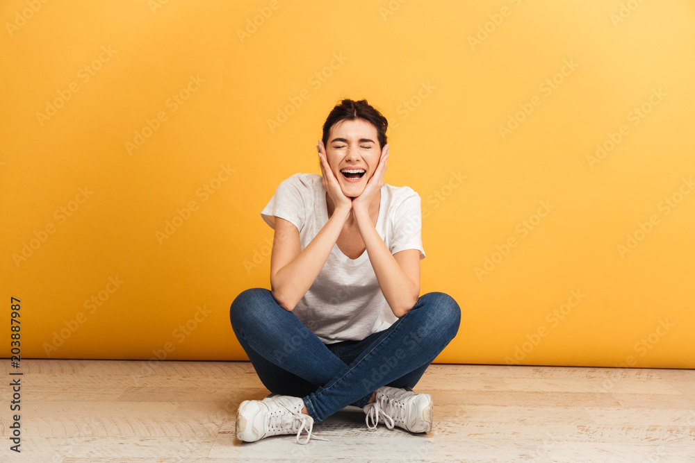 Portrait of an excited young woman sitting with legs crossed