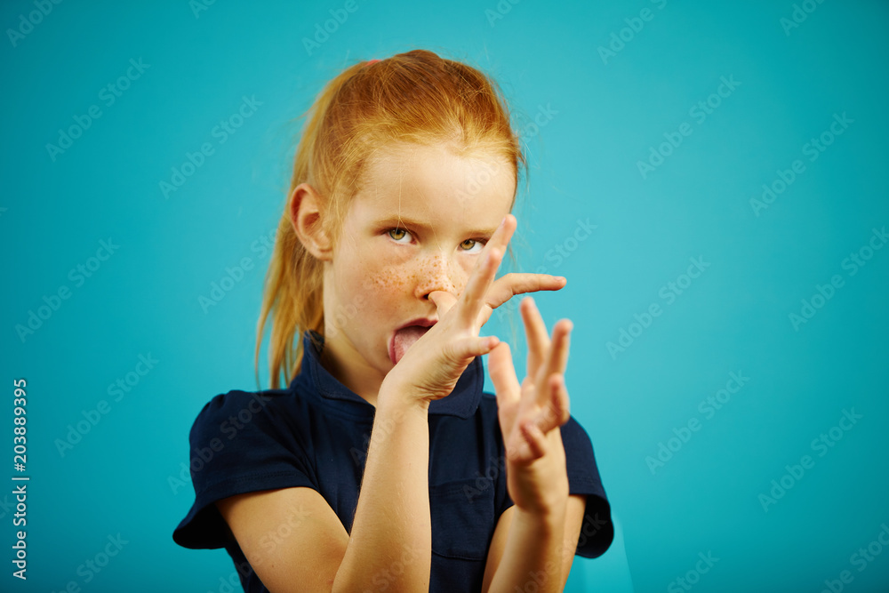 Funny girl teases you, stick tongue out and shows fingers naughty gestures on blue isolated background. Funny girl teases you, stick tongue out and shows fingers naughty gestures on blue isolated background.