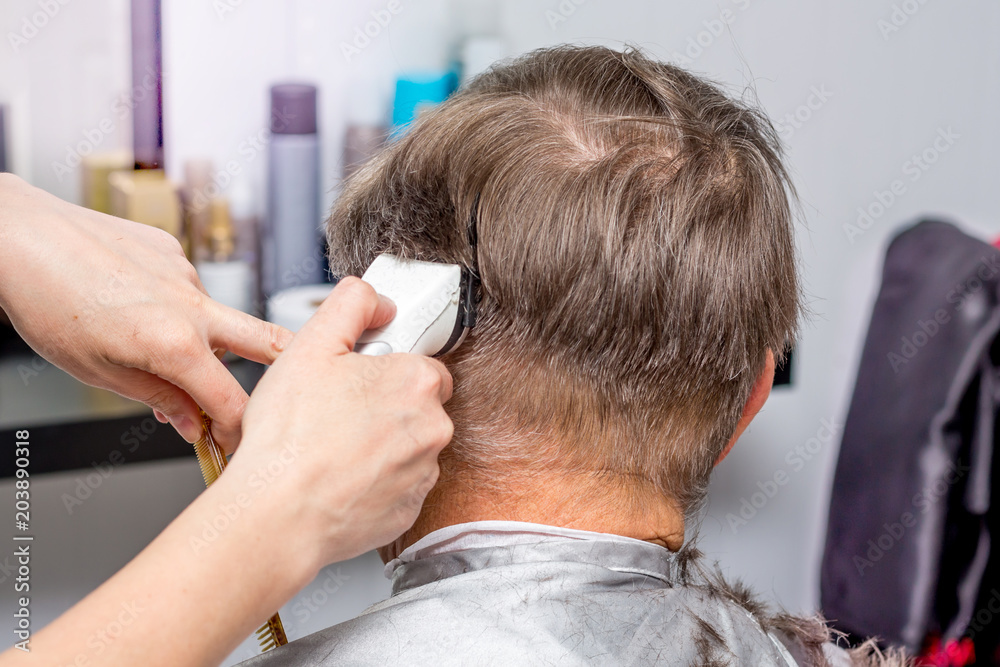 Fototapeta premium Hairdresser makes stylish hairstyle for an elderly man_