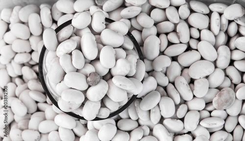 Close up on a raw organic white black beans in a glass with bean background. Macro. Healthy dietary food rich in microelements cellulose and vitamins. Vegeterian. vegetable diet. photo