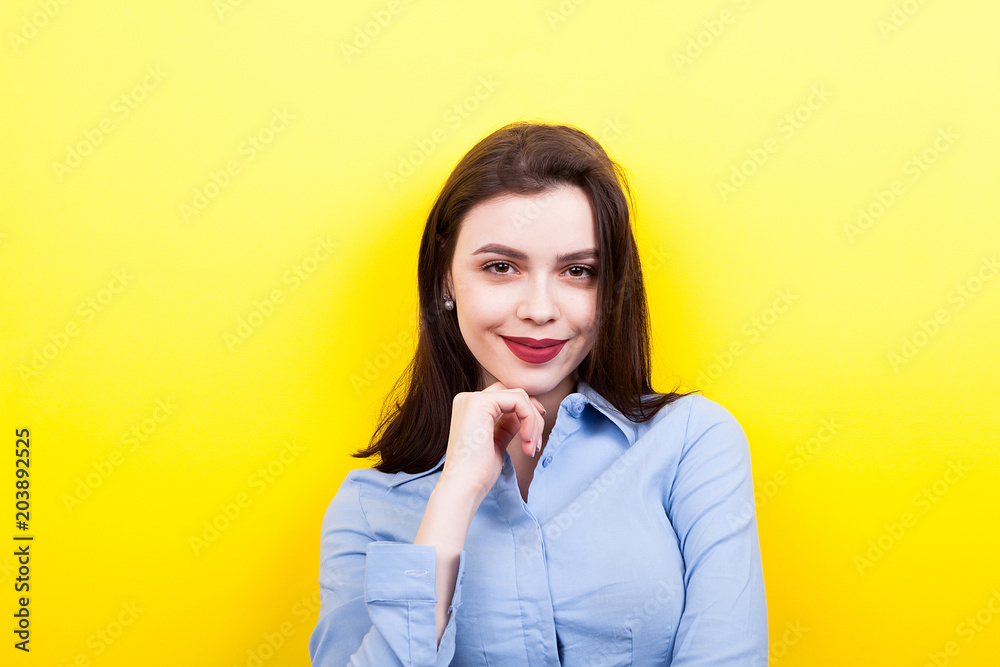Happy woman wearing a blue business shirt on yellow background
