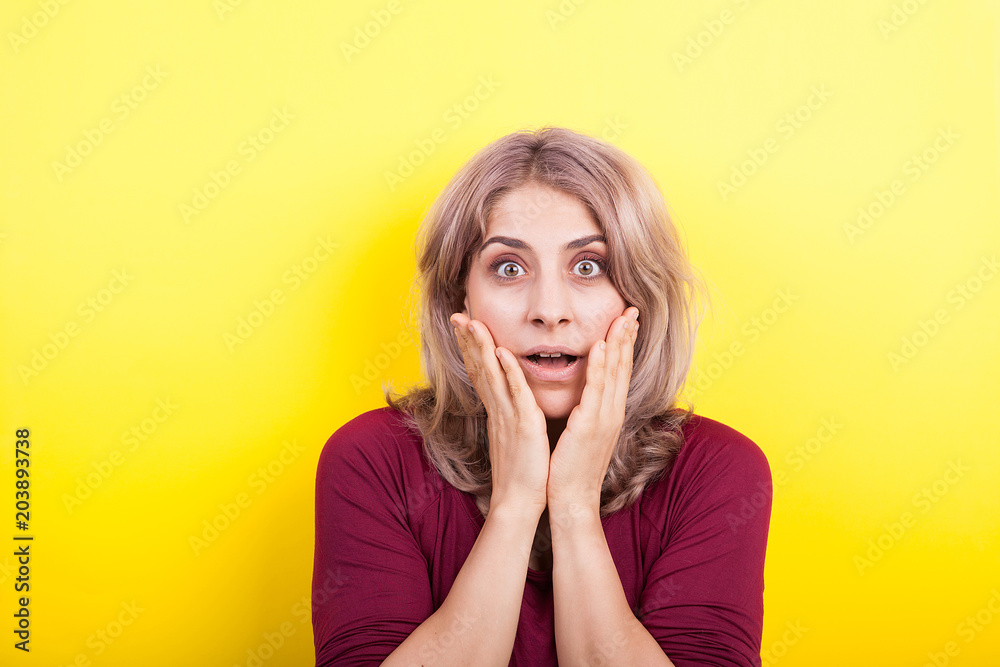 Beautiful blonde woman surprised on yellow background in studio photo Beautiful blonde woman surprised on yellow background in studio photo