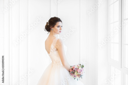 Obraz na płótnie Beautiful brunette woman with bouquet posing in a wedding dress